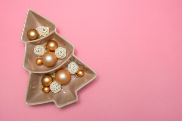 Pink background with gold balls, porcelain dish and packing tape. New Year's decoration. Background. Christmas. Spruce.