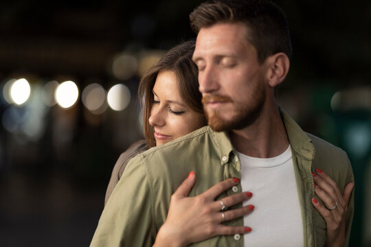 Man with eyes closed being embraced by girlfriend