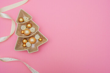 Pink background with gold balls, porcelain dish and packing tape. New Year's decoration. Background. Christmas. Spruce.