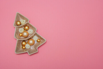 Pink background with gold balls, porcelain dish and packing tape. New Year's decoration. Background. Christmas. Spruce.