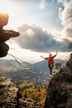Woman with arms raised slacklining amidst mountains at Baden-Baden, Germany