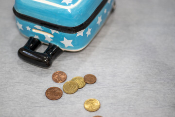 travel suitcase  piggy bank down on gray paper background euro coins scattered.kid hand putting...