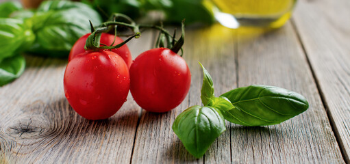 Fresh cherry tomatoes, basil leaves, mozzarella cheese and olive oil on old wooden background. Caprese salad ingredients. Selective focus.