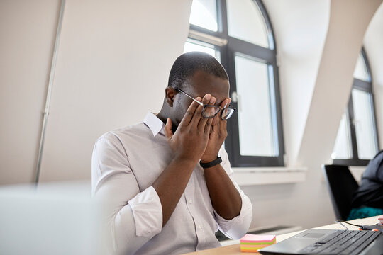 Tired male entrepreneur rubbing eyes while sitting at office