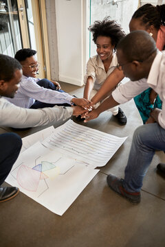 Male and female entrepreneurs stacking hands after meeting in office
