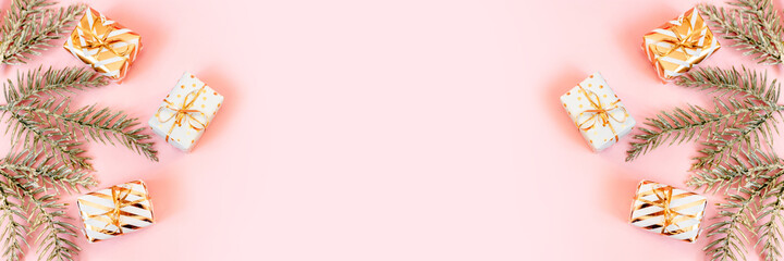 White gift boxes with golden bow with snowy fir branches on pastel pink background. Christmas, new year, festive, holiday, celebration or winter background with copy space. Top view, flat lay Banner