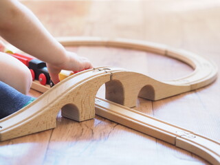 child plays in the children's wooden railroad in home room