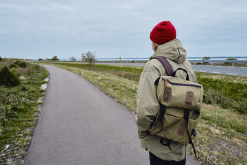 A man with a backpack walks along an empty road. Scenic view along the new route. To choose a new path of the road. Passion for travel. Travel, adventure, lifestyle