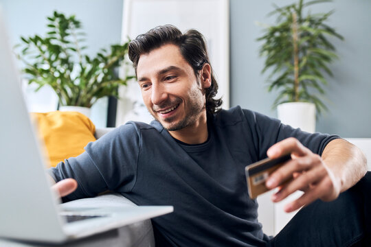 Man with credit card using laptop at home
