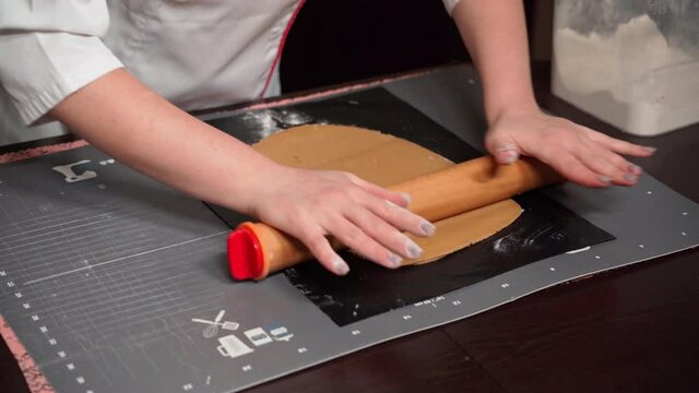 Step-by-step recipe for making Christmas cake. A professional pastry chef rolls out shortbread dough with a rolling pin