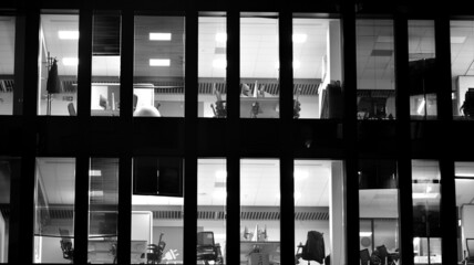 Corporate building at night - business concept. Glass wall office building .Modern office windows of skyscraper glowing at night. Black amd white.