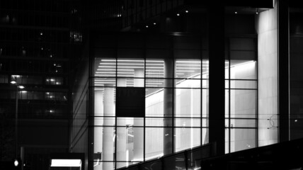Skyscraper lobby in  business district. Big glass windows in commercial skyscraper at night. Black and white.
