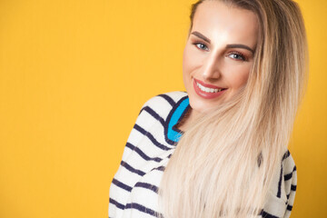 Face of nice girl keeps chin on shoulder, isolated on yellow background. Closeup portrait of a cheerful woman