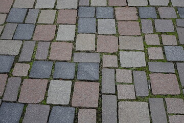 Paving of red, yellow and gray granite cobblestones and moss in the gaps, Hildesheim, Lower Saxony, Germany
