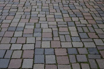 Paving of red, yellow and gray granite cobblestones and moss in the gaps, Hildesheim, Lower Saxony, Germany