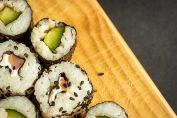 sushi rolls sesame wrapped on wooden board closeup
