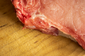 fresh raw pork chops on wooden cutting board closeup