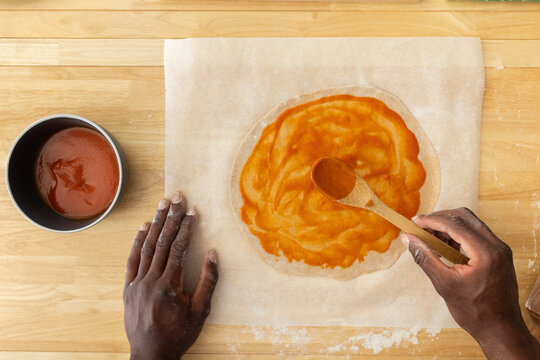 Man spreading sauce while making pizza in kitchen