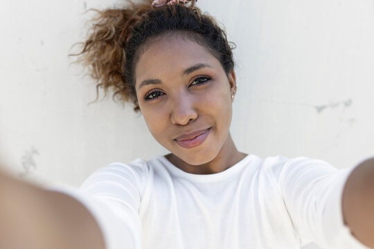 Woman taking selfie in front of white wall