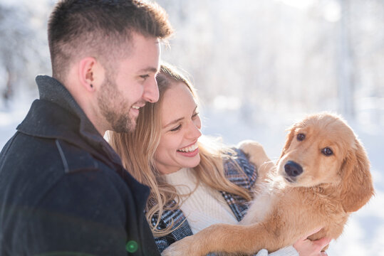 Smiling couple looking at dog during winter