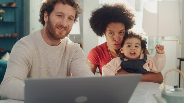 Father, Mother and Young Son Use Laptop Computer at Home Apartment. Happy Mixed Race Family with Loving Child Watch Cartoons, Shop Baby Products Online, Look at Funny Pictures or Play Video Games.