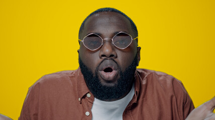 Portrait of serious african man showing cross hand in yellow background.