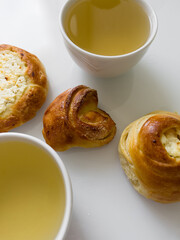 Two cups of hot tea with delicious buns for tea party on cold morning