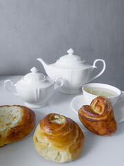 Cup for tea, teapot, sugar bowl, delicious buns on the table for morning tea