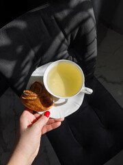 Woman holding cup of tea with delicious bun 