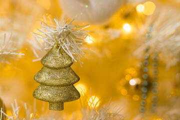 Close up of gold tree toy and garlands on white yellow Christmas tree