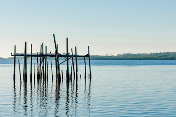 Remnants of a fish shanty in Cedar Key, Florida with blue water and sky.