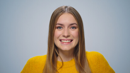 Portrait of happy attractive woman smiling at camera on grey background. 