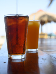 Two glasses of passionfruit juice and cola on exotic beach