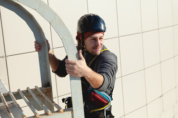 Young worker looks to the right, holding onto the ladder