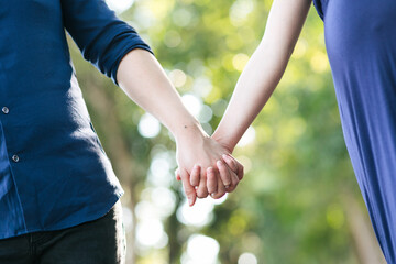 Future parents holding hands with isolated blur garden background