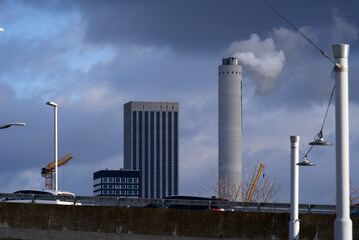 Chimney of waste incineration plant with smoke and silo tower with solar panels at industrial...