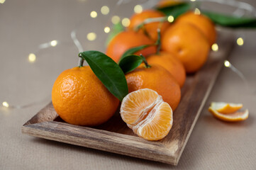 Photo of juicy orange mandarins with fresh green leaves with bokeh on background