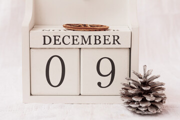 December 9th. Day 9 of month, calendar and a fir-cone  on white background.  White block calendar...