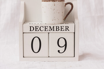 December 9th. Day 9 of month, calendar and a cup of coffee or tea on white background.  White block...