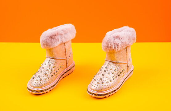 pair of fashionable winter beige ugg boots on yellow background, new pair