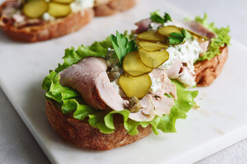 Cold baked pork, pickle and lettuce with remoulade (danish tartar sauce) Smorrebrod. Danish open faced sandwich. Selective focus - 473580474