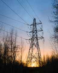 High voltage power lines at sunset in autumn forest, High voltage electric transmission tower