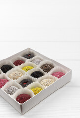 Box of vegan sweets energy balls on white wooden table.