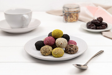 Colorful vegan candies energy balls on a plate on a white table.