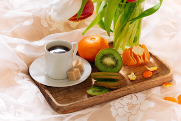 breakfast in bed with fruits, coffee and flowers on a tray. Romantic breakfast in bed