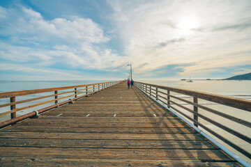 Wide long wooden pier on the beach with beautiful cloudy sky on background, California