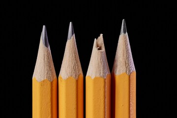 Pencil tips on black background, one broken