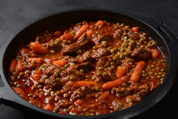 Beef stew, meat ragout with carrots, onions and green peas. Meat stew with vegetables in tomato sauce in a bowl.