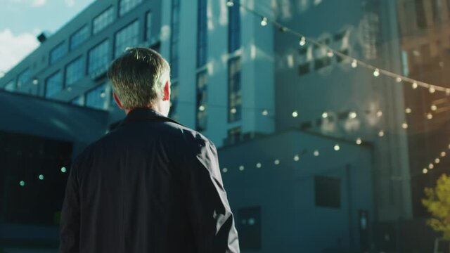 Grey-haired mature caucasian man walking down business district. Handsome employer businessman in sunny street. Personality. Success.