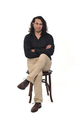 front view of a man with shirt, shoes and pants  sitting on chair,arms and legs crossed looking at...